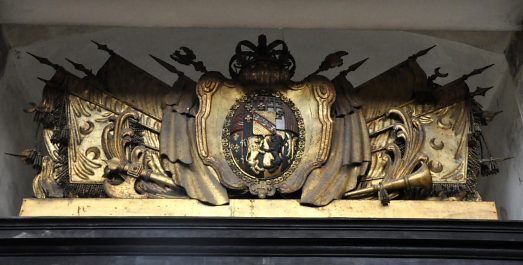 Une série d'emblèmes et de drapeaux surmonte la porte de la  chapelle ducale