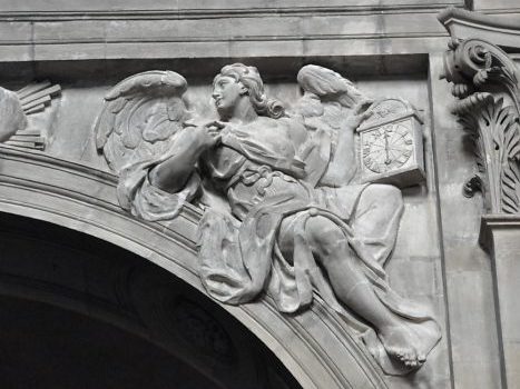 Haut-relief sur l'écoinçon d'une arcade : un ange tenant  une horloge.