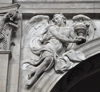 Haut–relief sur l'écoinçon d'une arcade : un ange tenant un ciboire.