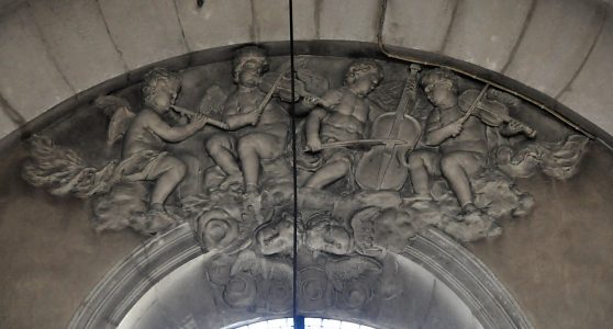 Angelots musiciens dans un décor baroque en stuc au–dessus d'une baie du transept