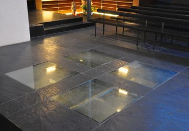 Depuis le sol de la nef on aperçoit le baptistère au niveau inférieur. Depuis le sol de la nef on aperçoit le baptistère au niveau inférieur.
