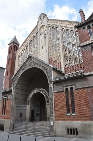 La façade de l'église et son beau fenestrage en ciment moulé