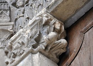 Sous le linteau du portail central, bas-relief d'un homme accroupi