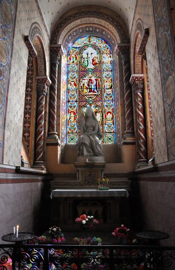 La chapelle axiale est dédiée à la Vierge.