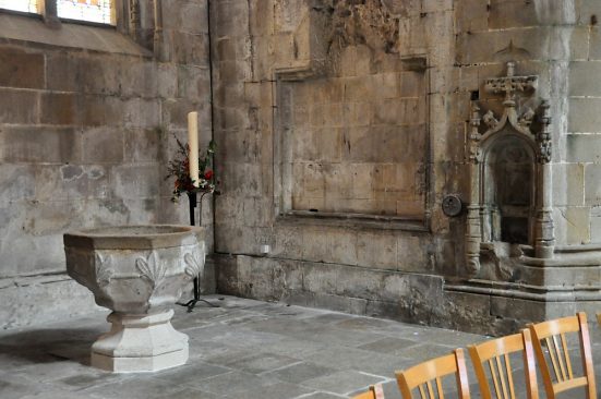 Éléments anciens dans l'avant–nef : cuve baptismale du XVe siècle servant de bénitier et, sur la droite, piscine