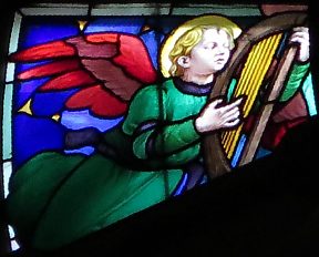 Un ange joue de la lyre dans la rosace de la Crucifixion